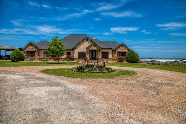 view of front of property with curved driveway, board and batten siding, a front yard, and stone siding