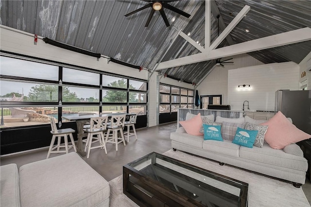 living area with beamed ceiling, a ceiling fan, high vaulted ceiling, and a wealth of natural light