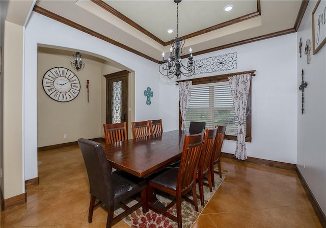 dining room with an inviting chandelier, crown molding, baseboards, a tray ceiling, and arched walkways