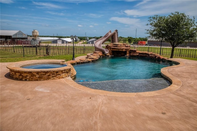 view of pool featuring fence, a yard, a water slide, and a pool with connected hot tub