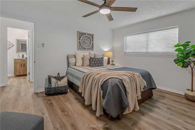 bedroom with a textured ceiling, connected bathroom, light hardwood / wood-style flooring, and ceiling fan