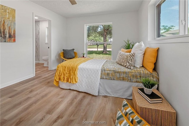 bedroom with connected bathroom, ceiling fan, light hardwood / wood-style floors, and a textured ceiling