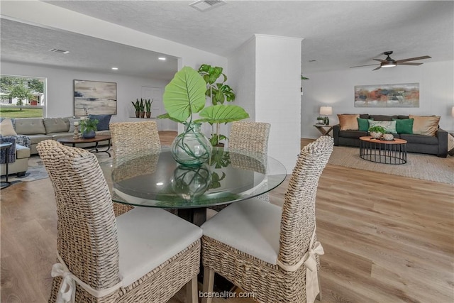 dining space with a textured ceiling, light wood-type flooring, and ceiling fan