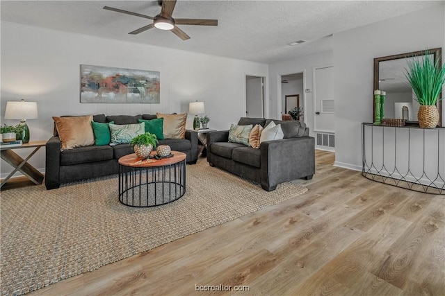 living room with a textured ceiling, light wood-type flooring, and ceiling fan