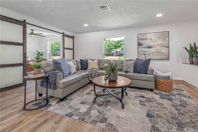 living room featuring a textured ceiling, a barn door, wood-type flooring, and a healthy amount of sunlight