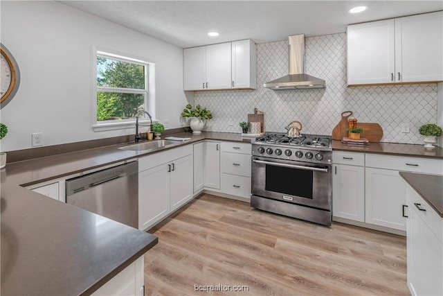 kitchen with wall chimney exhaust hood, sink, white cabinetry, and stainless steel appliances