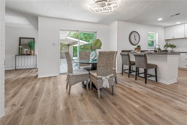 dining room featuring a textured ceiling and light hardwood / wood-style flooring