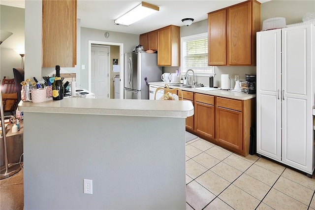 713 Broadmoor Dr, Bryan, TX 77802 - kitchen featuring freestanding refrigerator, a sink, light countertops, washer / clothes dryer, and a peninsula