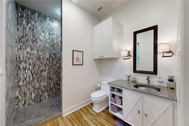 bathroom featuring hardwood / wood-style flooring, vanity, toilet, and a shower