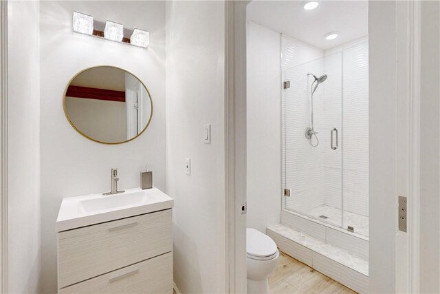 bathroom featuring vanity, toilet, and a shower with door