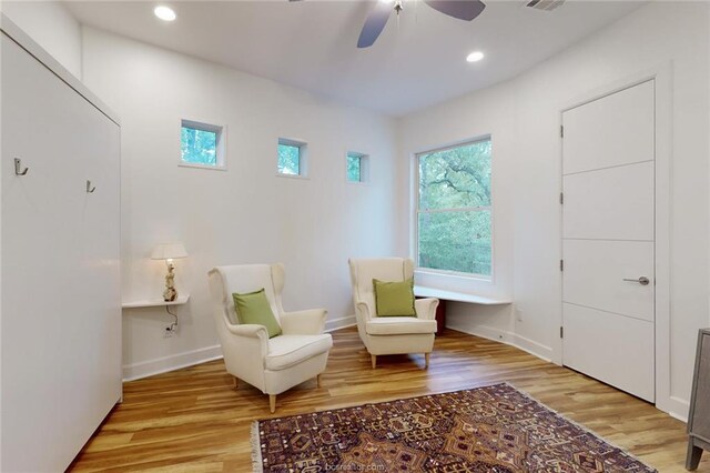 living area featuring light wood-type flooring and ceiling fan