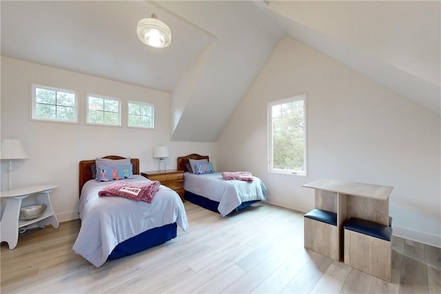 bedroom featuring light hardwood / wood-style floors, lofted ceiling, and multiple windows