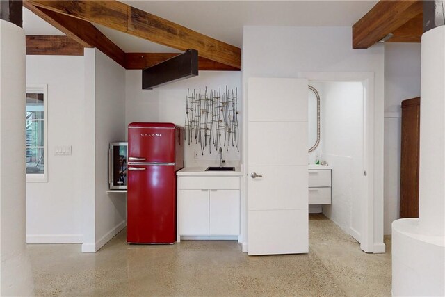 bar with beam ceiling, refrigerator, white cabinetry, and sink