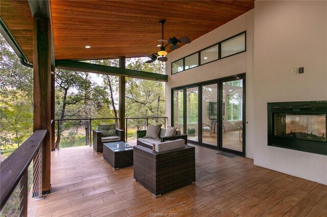 wooden deck featuring an outdoor living space with a fireplace and ceiling fan