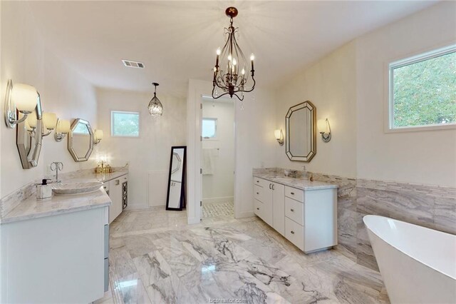 bathroom featuring a bath, vanity, tile walls, and a notable chandelier