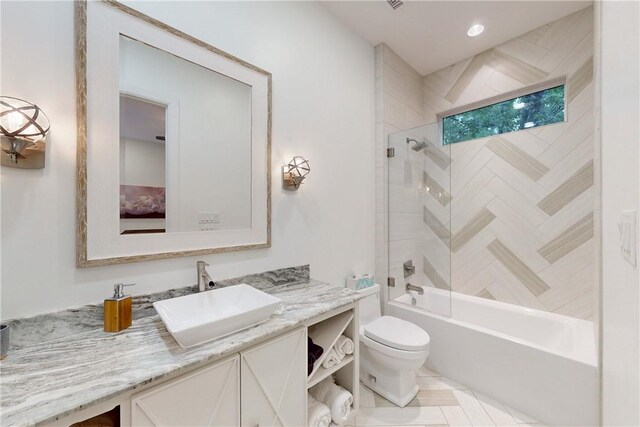 full bathroom with tile patterned flooring, tiled shower / bath combo, toilet, and vanity