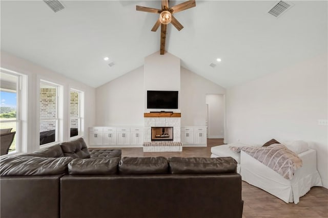 10146 Henley Cv, Iola, TX 77861 - living room with beam ceiling, a ceiling fan, wood finished floors, a stone fireplace, and high vaulted ceiling