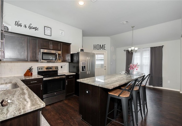 122 Dove Ct, Navasota, TX 77868 - kitchen with appliances with stainless steel finishes, a chandelier, dark wood-style flooring, a center island, and tasteful backsplash