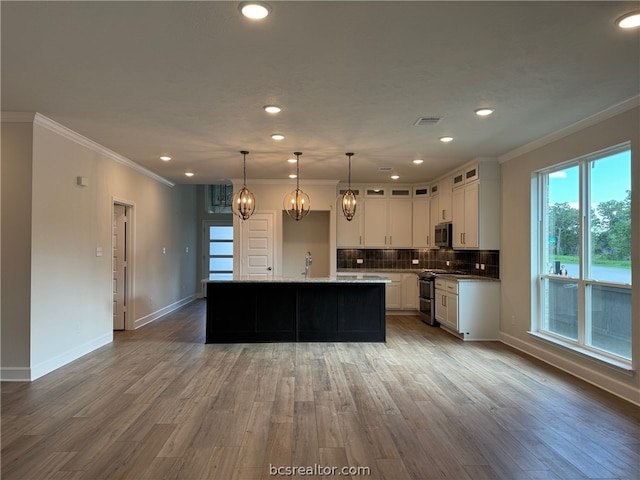 kitchen with white cabinets, hardwood / wood-style floors, and an island with sink