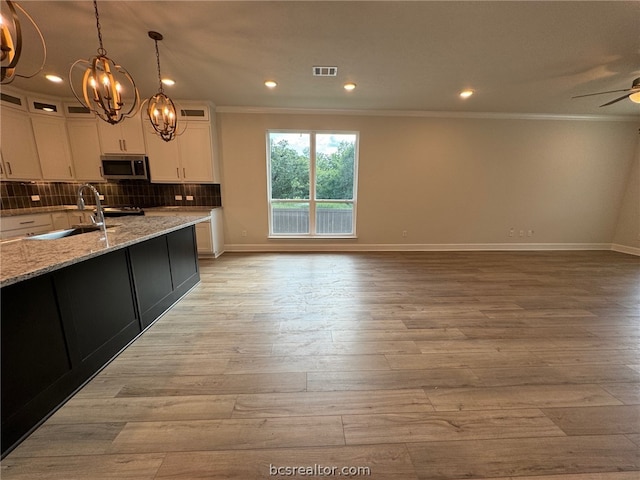 kitchen with white cabinetry, sink, light stone counters, and light hardwood / wood-style floors