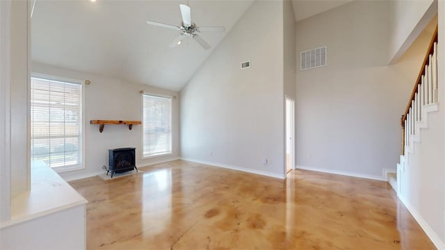 unfurnished living room with visible vents, stairway, a wood stove, ceiling fan, and concrete flooring