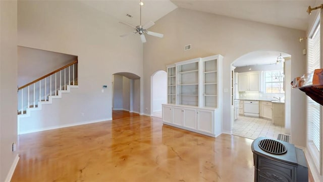 unfurnished living room with arched walkways, visible vents, a ceiling fan, stairs, and baseboards