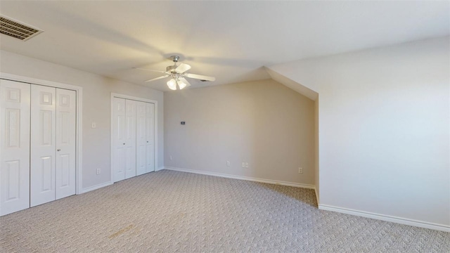 interior space featuring light carpet, baseboards, visible vents, ceiling fan, and multiple closets