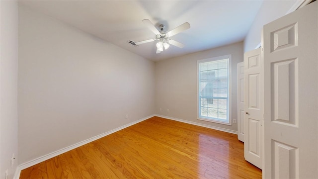 empty room with ceiling fan, wood finished floors, visible vents, and baseboards