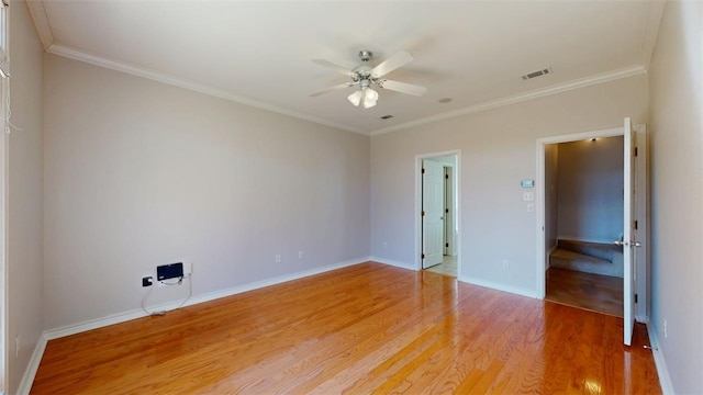 empty room with a ceiling fan, crown molding, baseboards, and wood finished floors