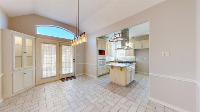 kitchen with island range hood, a kitchen island, glass insert cabinets, oven, and pendant lighting