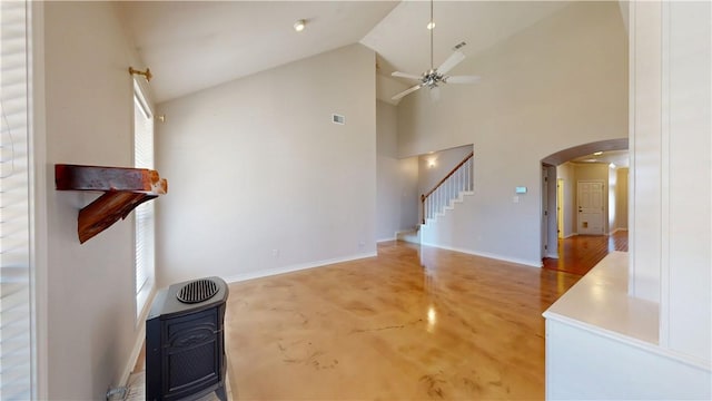 living area featuring arched walkways, ceiling fan, high vaulted ceiling, baseboards, and stairs