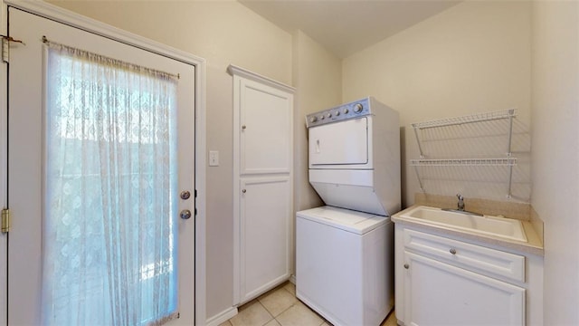 laundry area featuring a sink, light tile patterned floors, and stacked washer / dryer