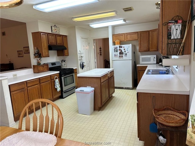 kitchen featuring sink, a center island, and white appliances