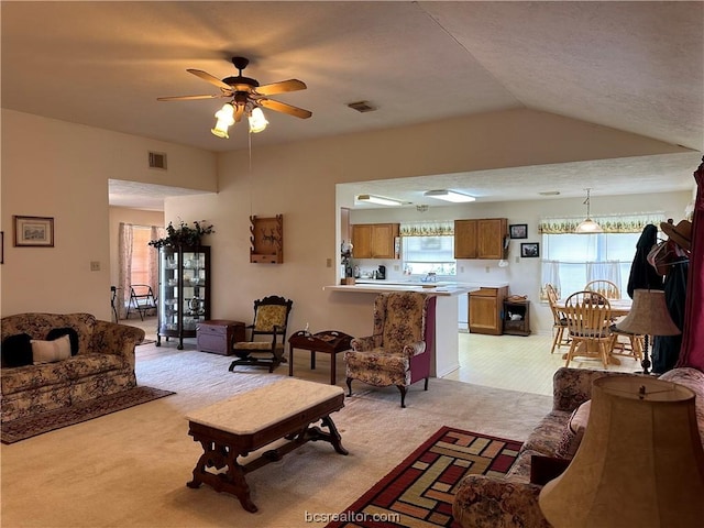 carpeted living room featuring plenty of natural light, ceiling fan, and vaulted ceiling