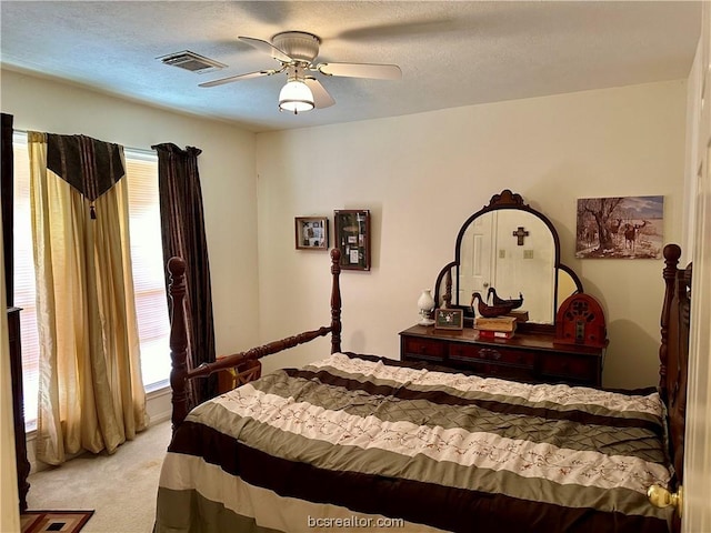 bedroom featuring a textured ceiling, ceiling fan, and light carpet