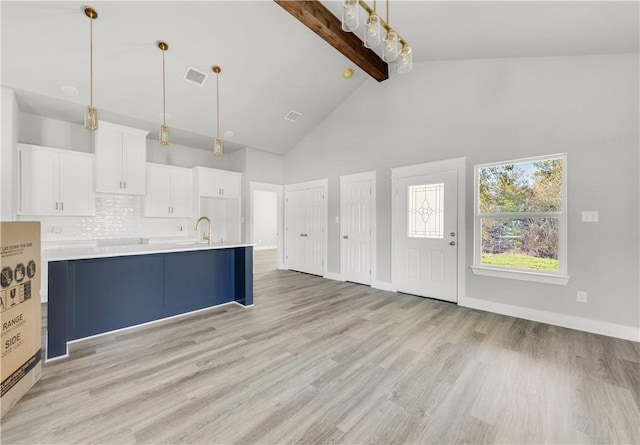 kitchen with white cabinetry, beamed ceiling, high vaulted ceiling, decorative light fixtures, and light wood-type flooring