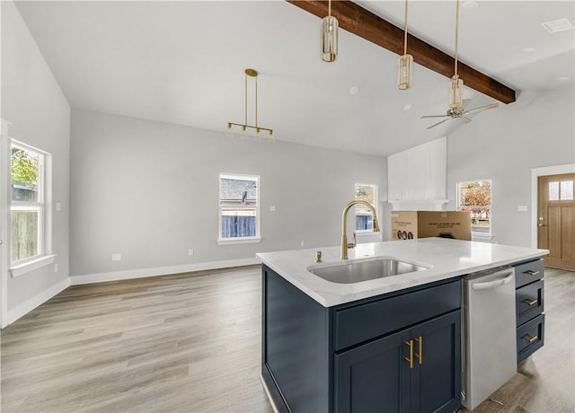 kitchen featuring sink, ceiling fan, an island with sink, beamed ceiling, and decorative light fixtures