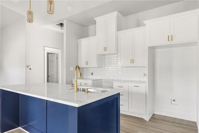 kitchen featuring white cabinetry, sink, backsplash, decorative light fixtures, and light wood-type flooring