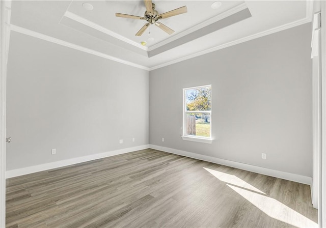 unfurnished room featuring ceiling fan, wood-type flooring, crown molding, and a tray ceiling