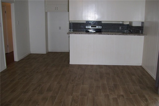 kitchen with white cabinets, dark stone counters, dark hardwood / wood-style floors, and electric range