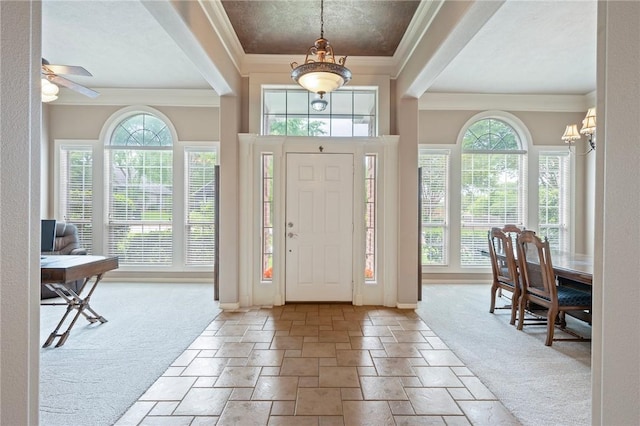 carpeted entryway featuring crown molding, baseboards, stone tile floors, and a notable chandelier