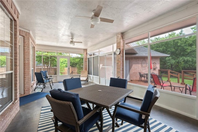 sunroom with outdoor dining area, a ceiling fan, and a wealth of natural light