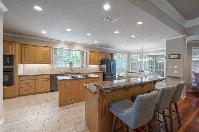 kitchen featuring crown molding, visible vents, a large island, a chandelier, and black appliances