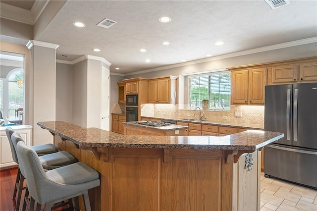 kitchen with a sink, recessed lighting, a kitchen island, visible vents, and black appliances
