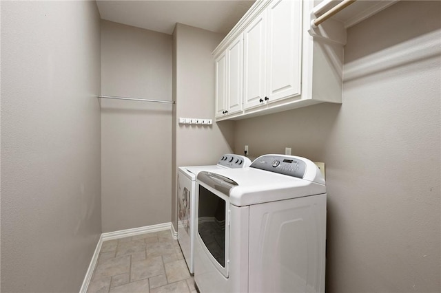 washroom featuring washing machine and clothes dryer, baseboards, stone finish flooring, and cabinet space