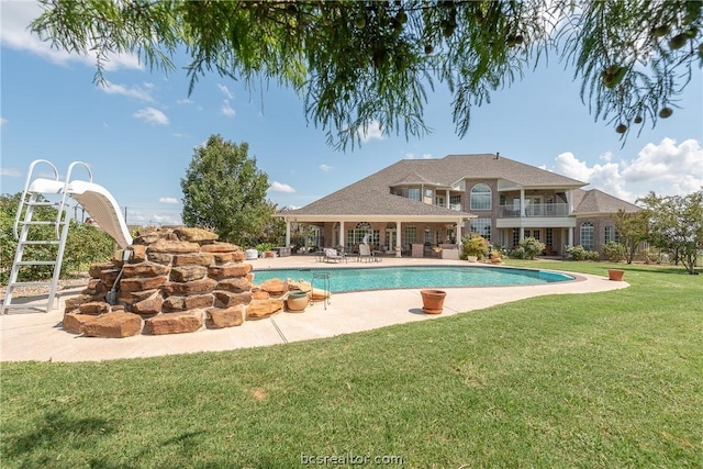 pool with a water slide, a patio, and a yard