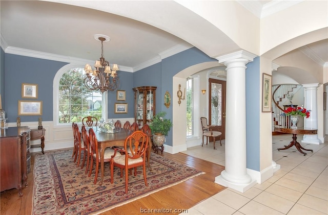 dining room with ornate columns, ornamental molding, a chandelier, and light wood-type flooring