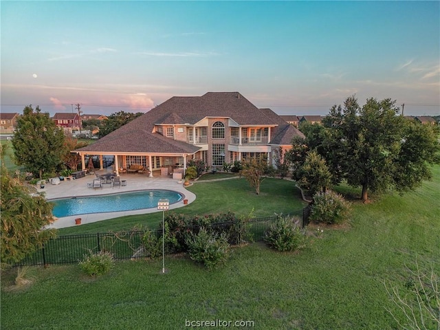 pool at dusk with a lawn, a patio area, and outdoor lounge area