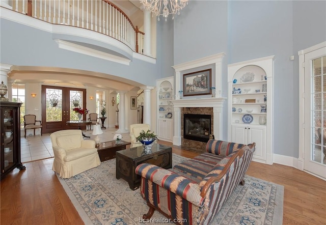 living room with built in features, a towering ceiling, and french doors