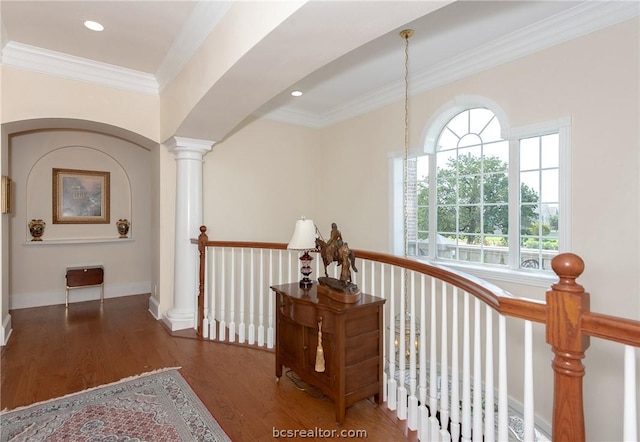 hall with ornate columns, wood finished floors, an upstairs landing, and crown molding